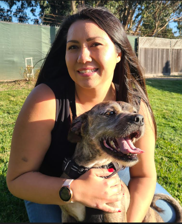 A woman is holding a dog in her arms in a field.