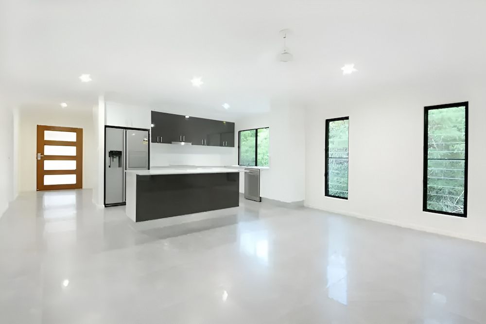 An Empty Living Room With A Kitchen And A Refrigerator — Reef Electrical in Cannonvale, QLD
