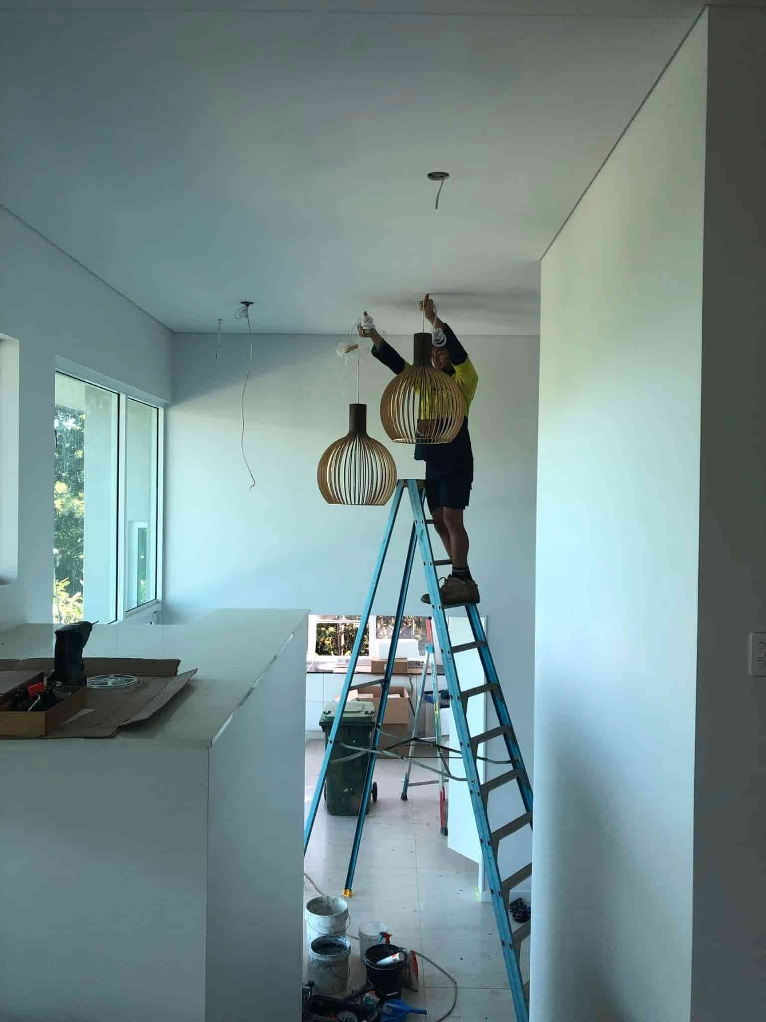 a Man is Standing on a Ladder in a Room — Reef Electrical in Bowen, QLD