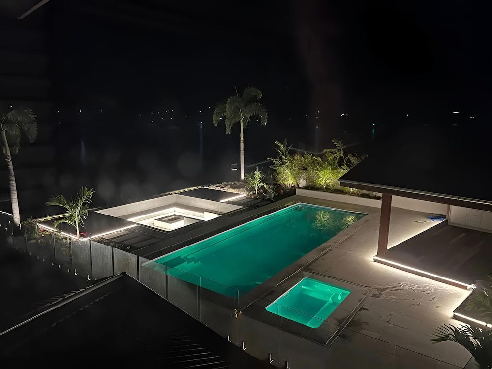 A Large Swimming Pool Is Lit Up At Night — Reef Electrical in Cannonvale, QLD