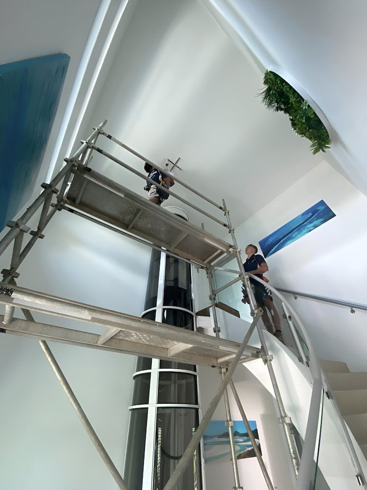 A Man Standing On A Staircase Next To A Scaffolding — Reef Electrical in Cannonvale, QLD