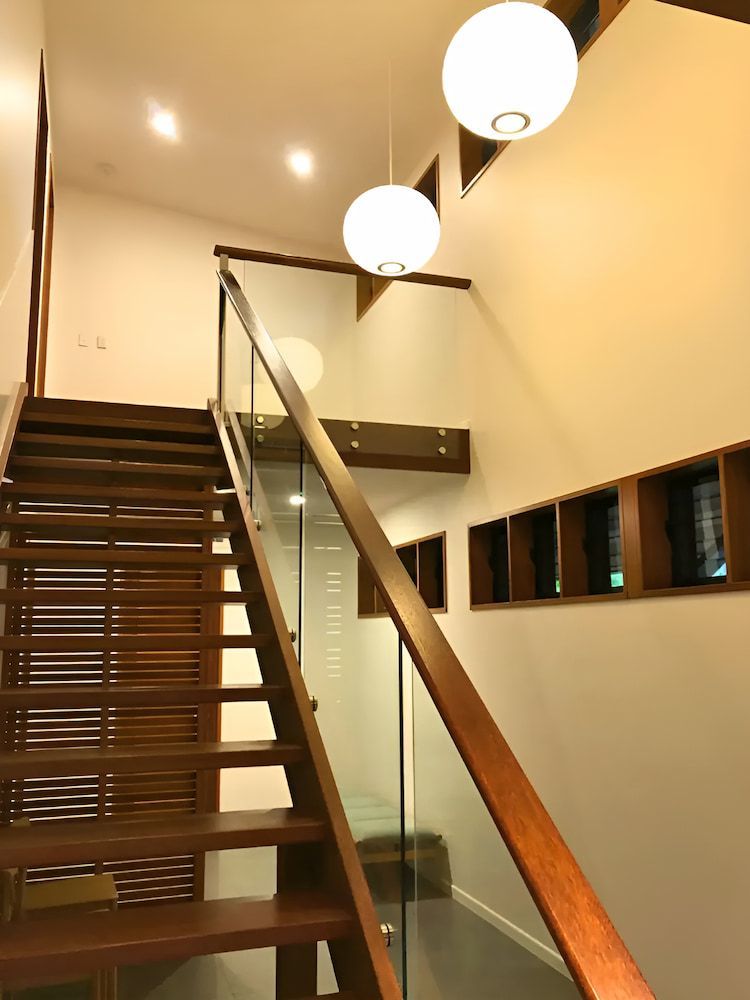 A Wooden Staircase With A Glass Railing In A Room — Reef Electrical in Cannonvale, QLD