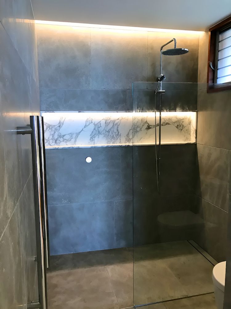 A Bathroom With A Walk In Shower And A Toilet — Reef Electrical in Cannonvale, QLD