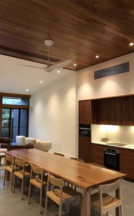 A Kitchen With A Long Table And Chairs And A Ceiling Fan — Reef Electrical in Cannonvale, QLD