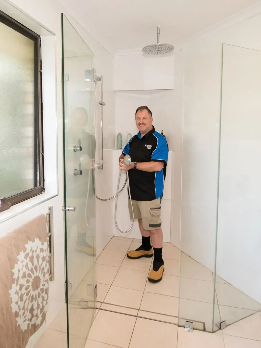 A man is standing in a shower holding a shower head  — Jobs2BDone in Bensville, NSW