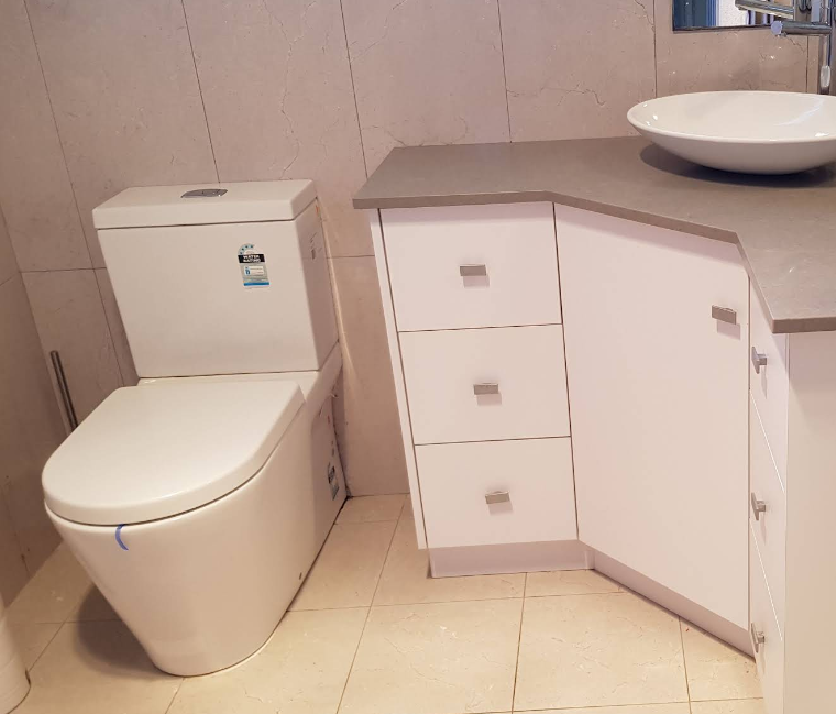 A bathroom with a toilet , sink and cabinets  — Jobs2BDone in Kincumber, NSW
