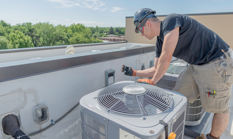 Technician servicing a rooftop air conditioner on a sunny day