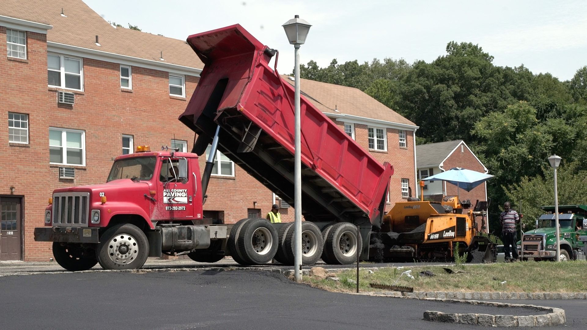 A red dump truck is parked in front of a brick building