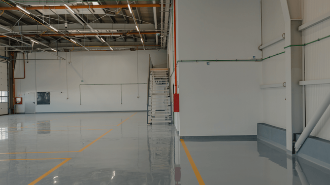 Large indoor space with a smooth, reflective epoxy-coated floor showing clean lines after an epoxy flooring service in Glendale, AZ
