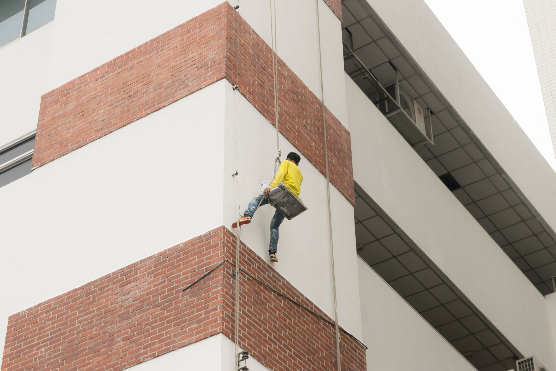A man is painting the exterior of a building. 