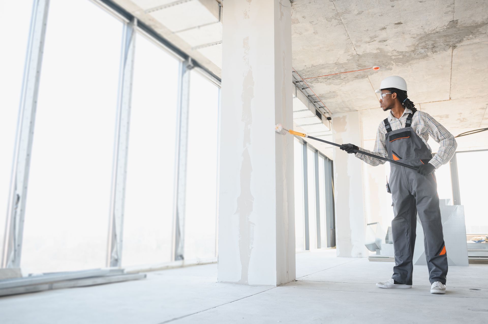 A professional contractor is painting walls in a building under construction A professional contractor is painting walls in a building under construction
