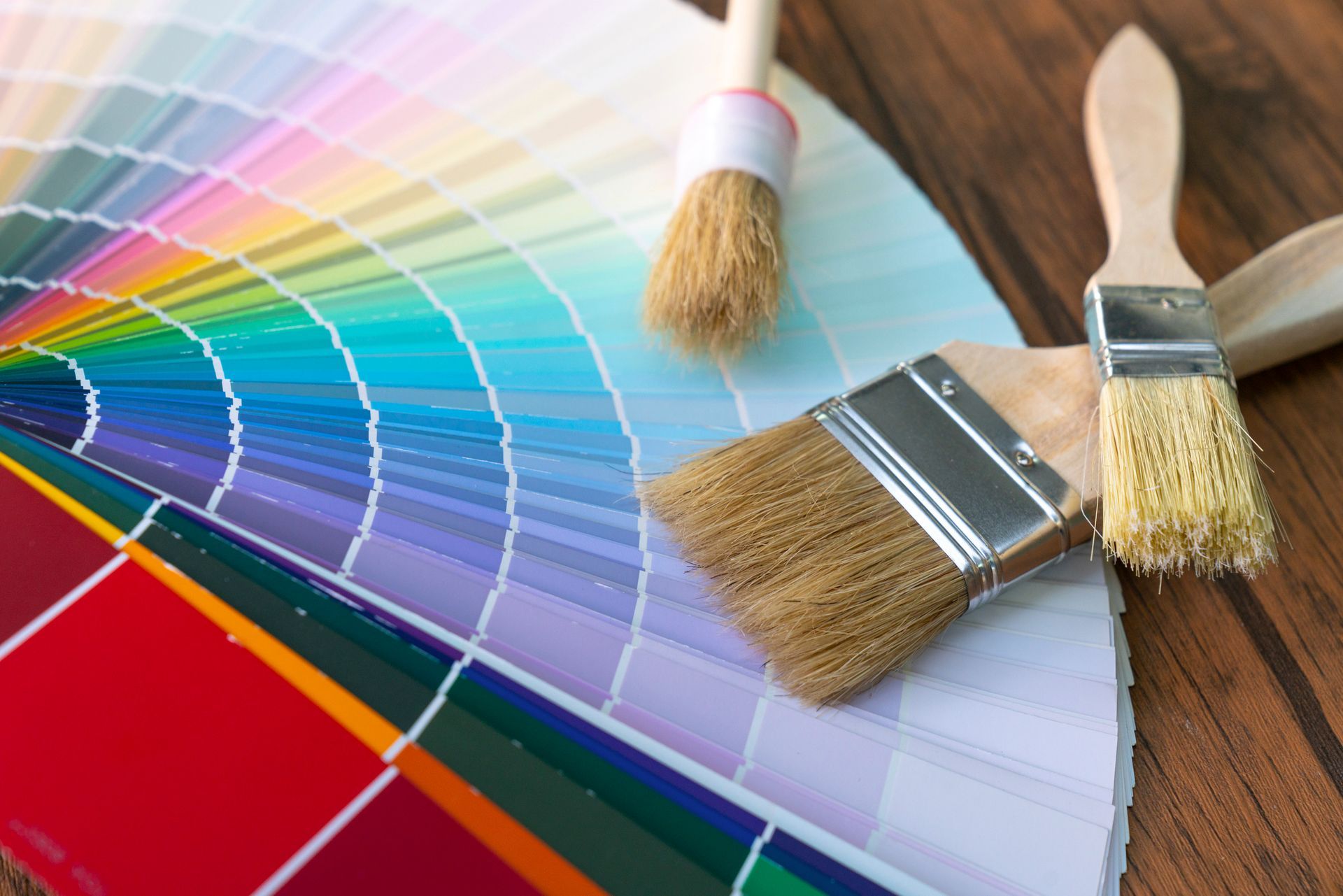 Painter's worktable with house project, color swatches, painting roller, and paint brushes.