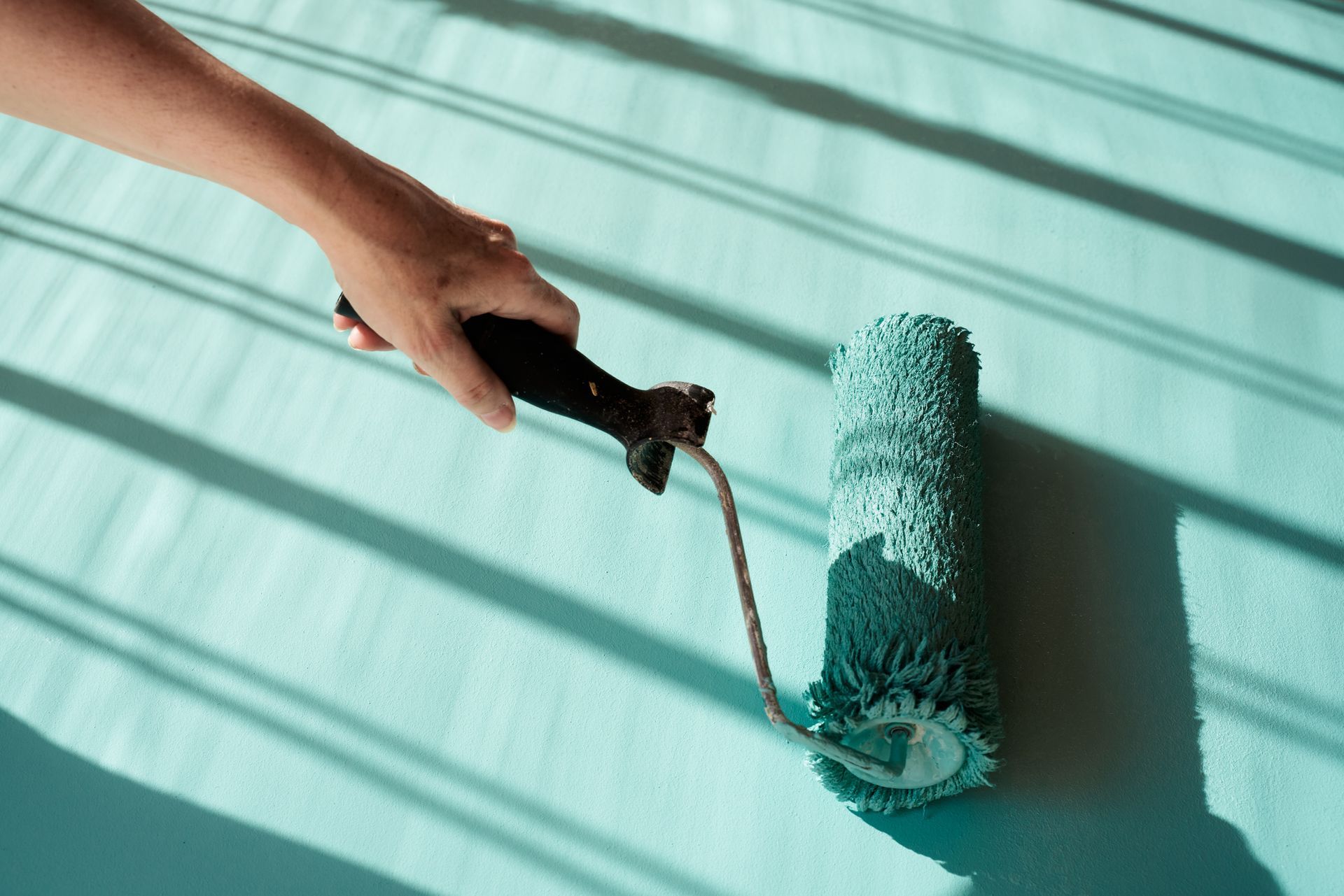 Caucasian painter roller painting the wall of a room.
