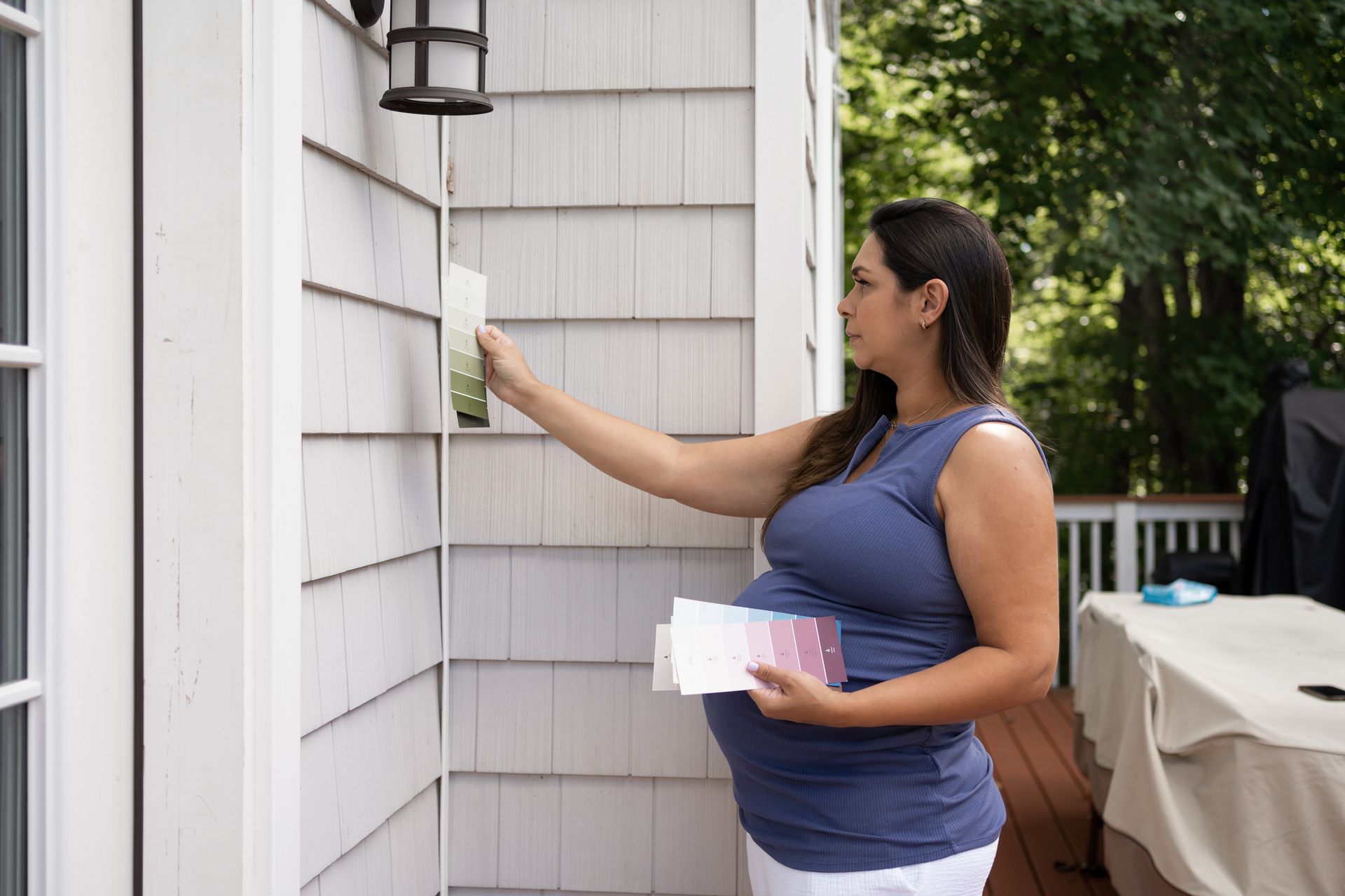 Pregnant woman holding paint samples outside her house. Pregnant woman holding paint samples outside her house.