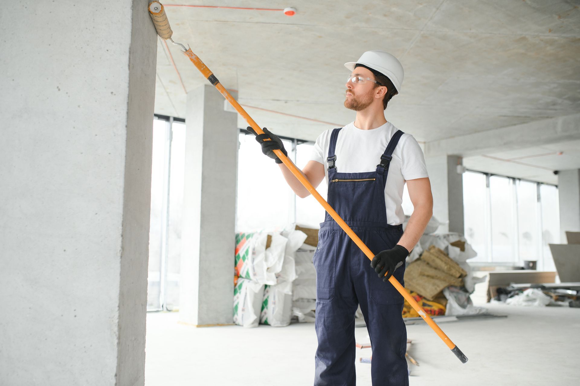 Painter providing commercial painting services in a new construction in Medina, OH, with paint roller.