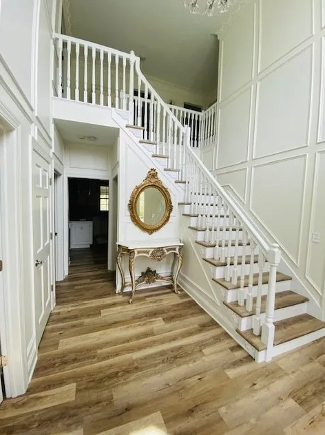 A hallway with stairs and a mirror on the wall.