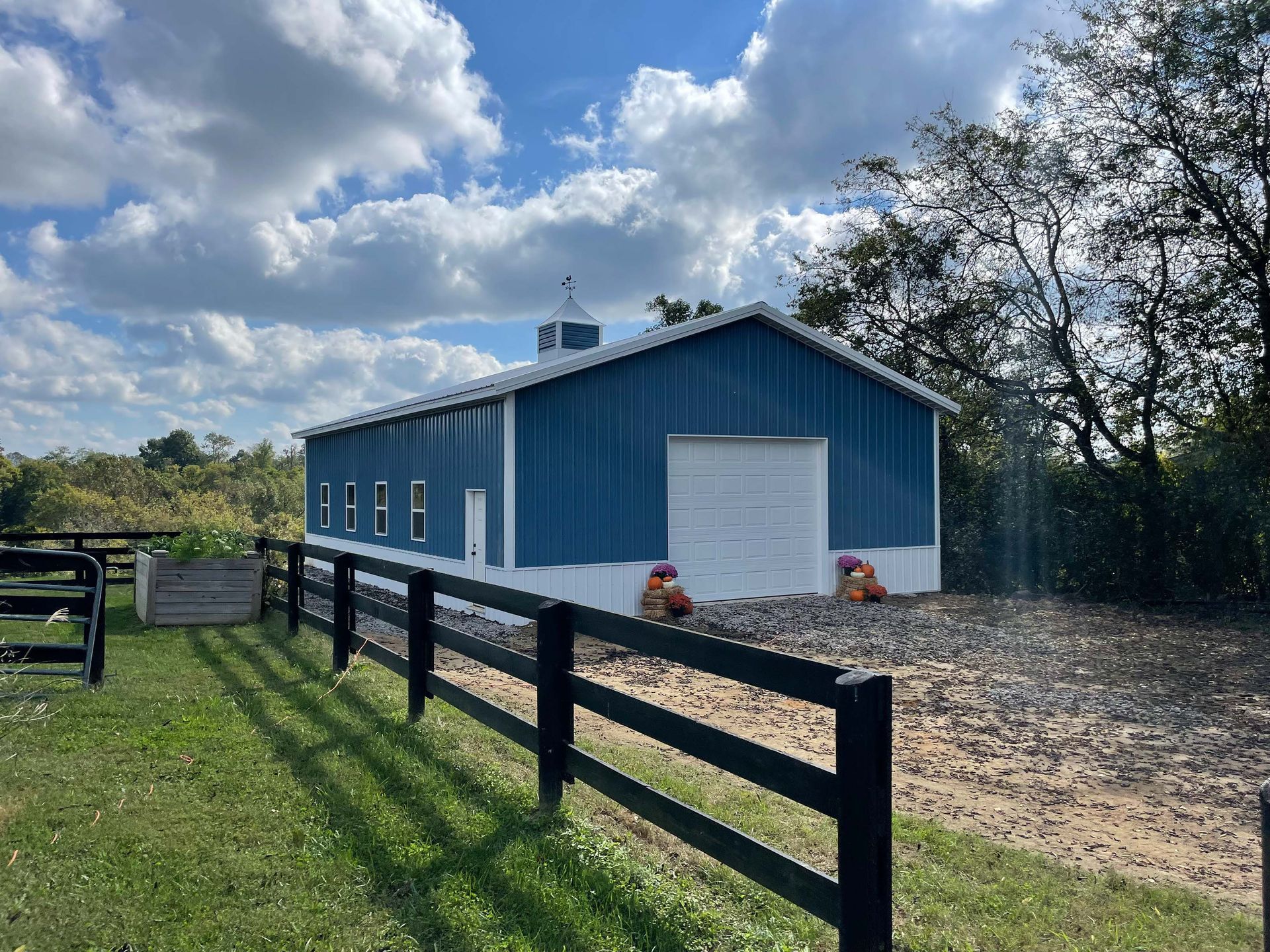 A blue and white barn with a black fence around it
