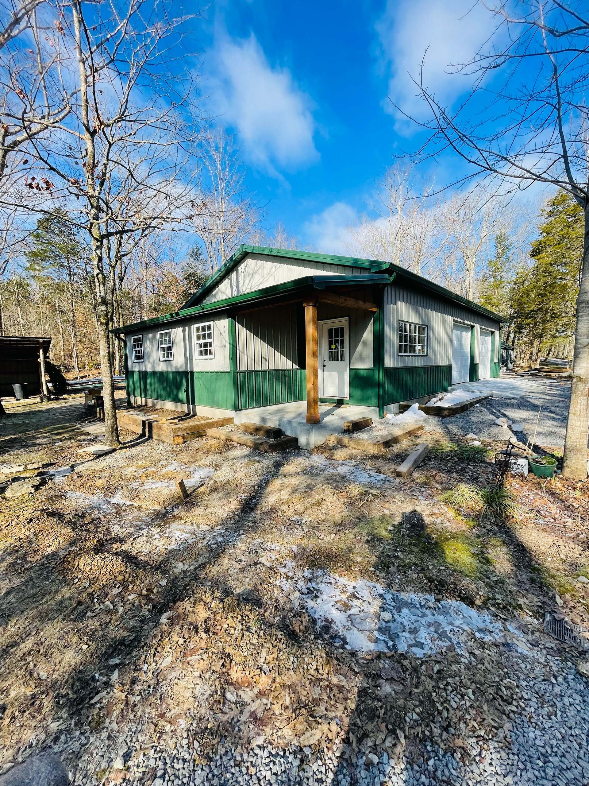 A small house with a green roof is sitting in the middle of a forest.
