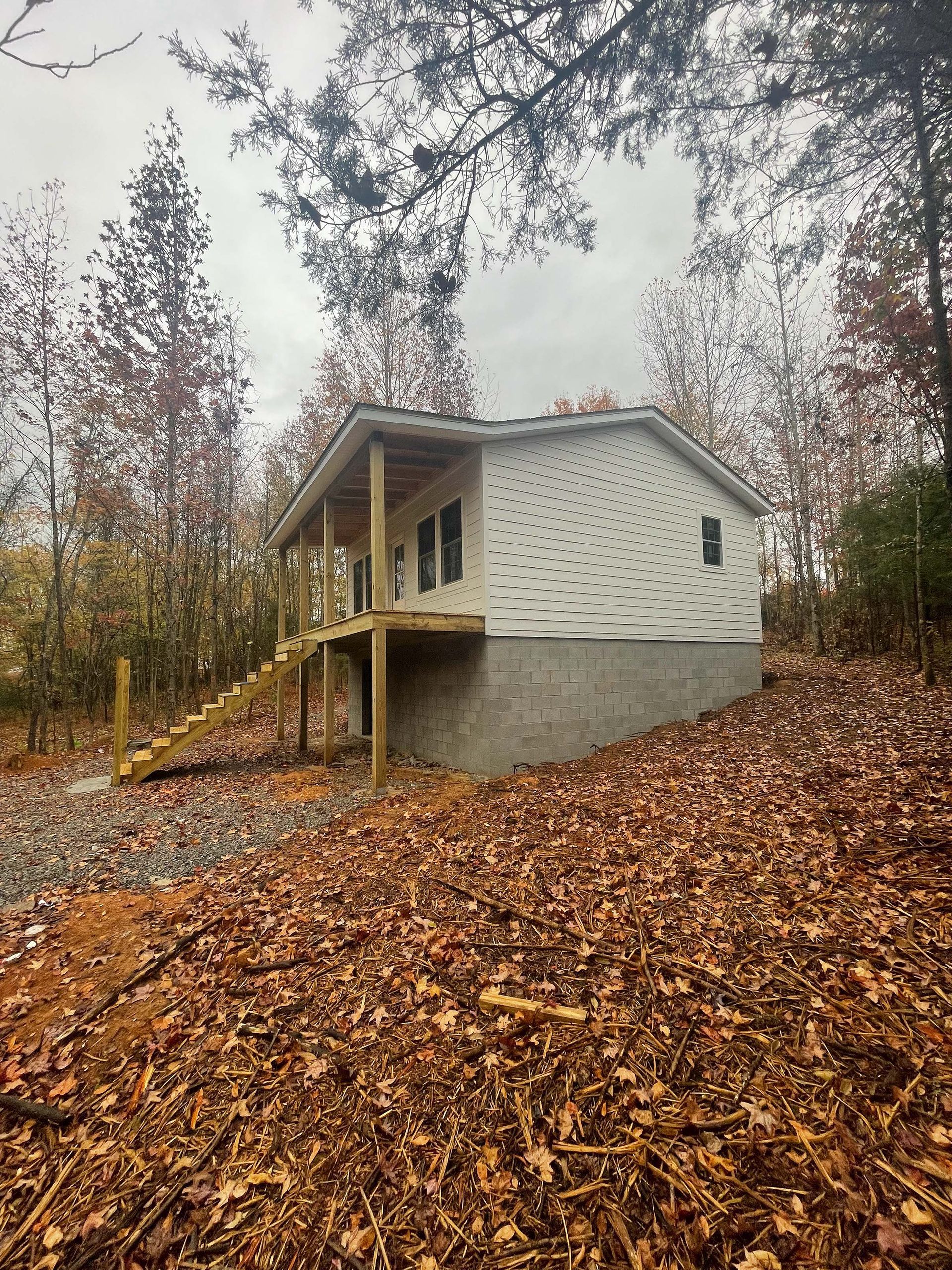 A small house is sitting on top of a hill surrounded by trees and leaves.
