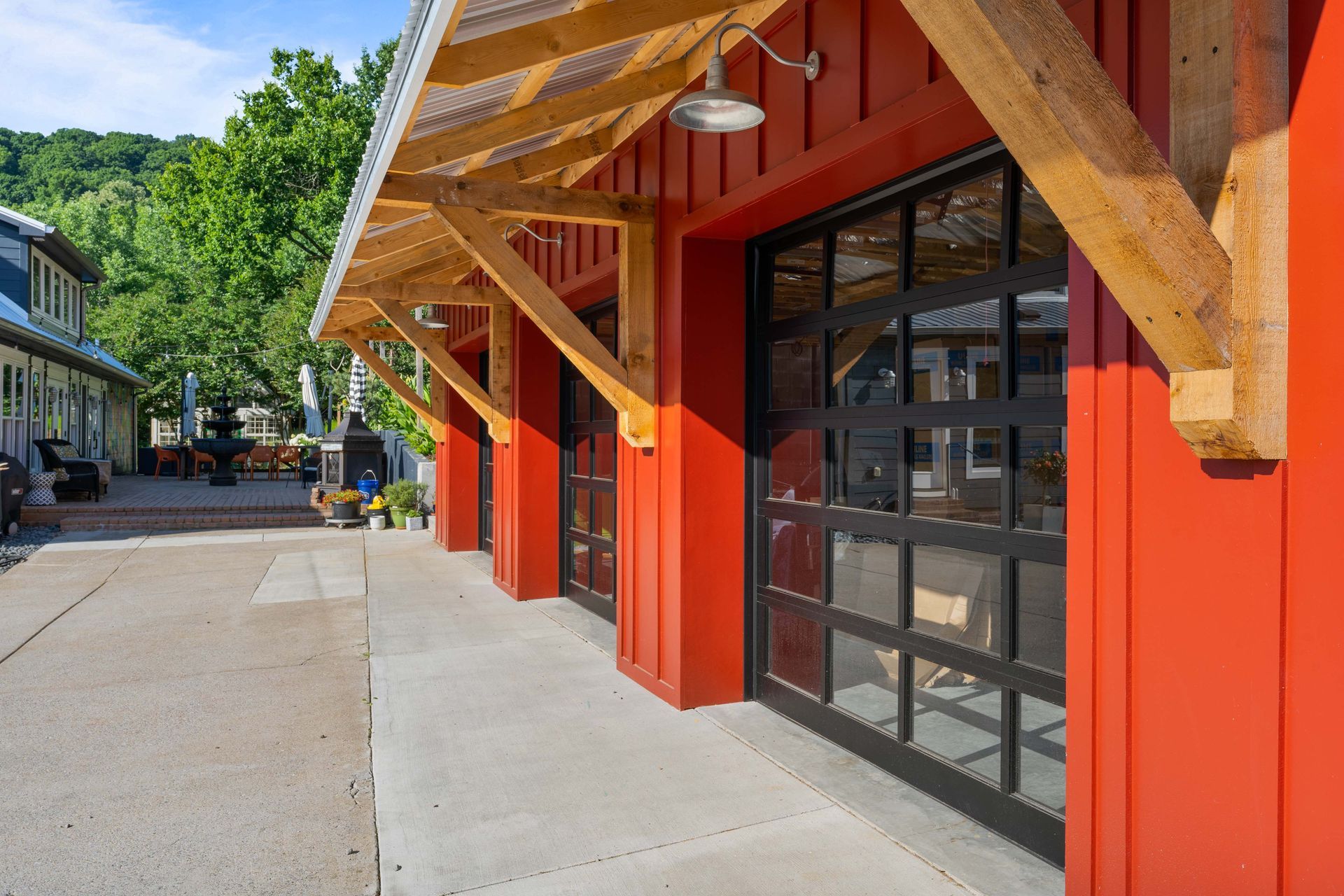 A red building with a black garage door and a wooden roof.