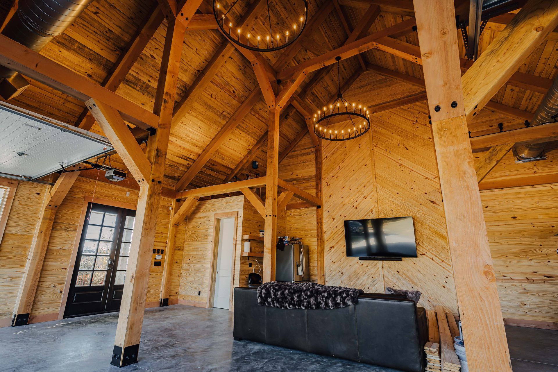 A living room with a couch , television , and wooden beams.