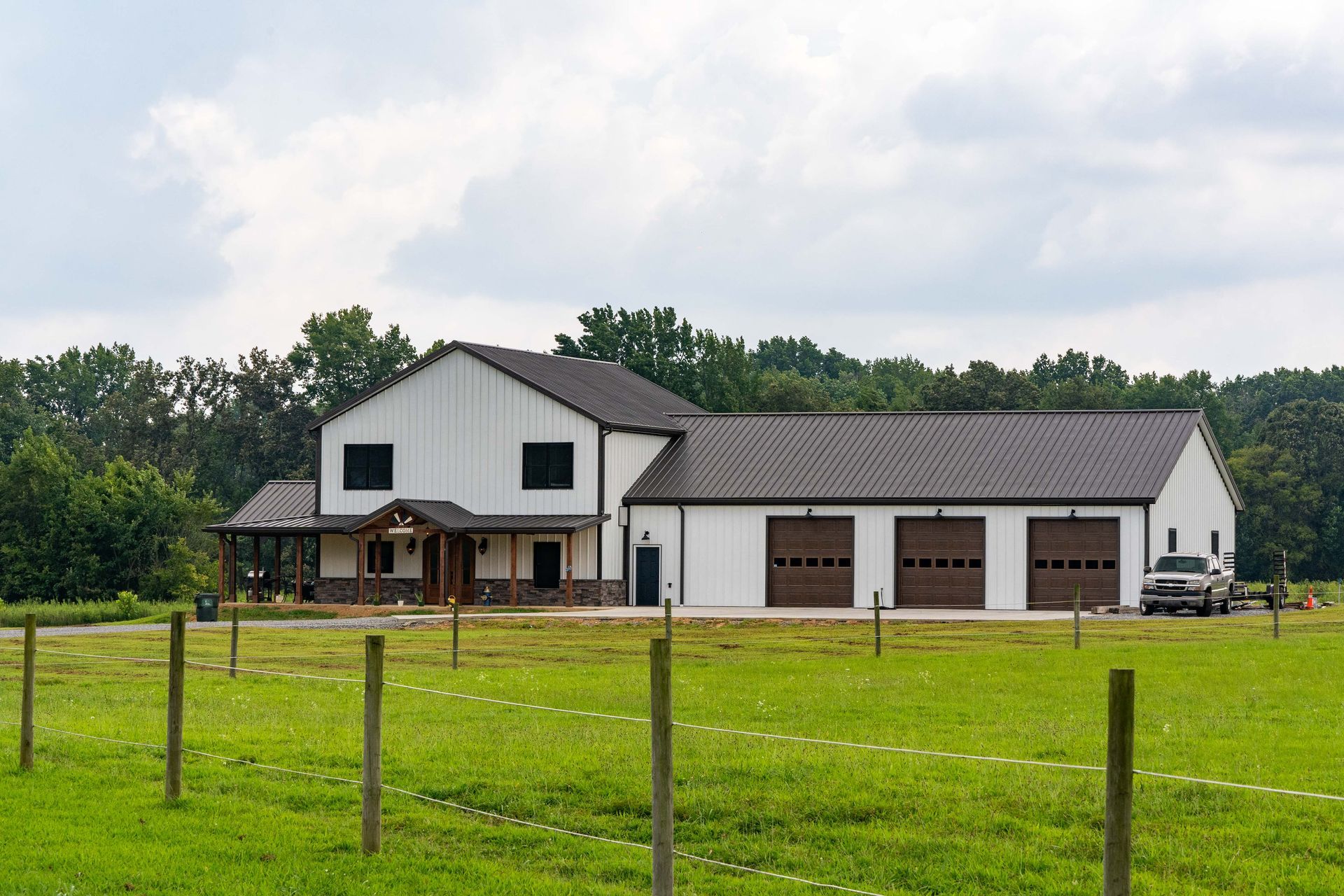 A large white house is sitting in the middle of a grassy field.