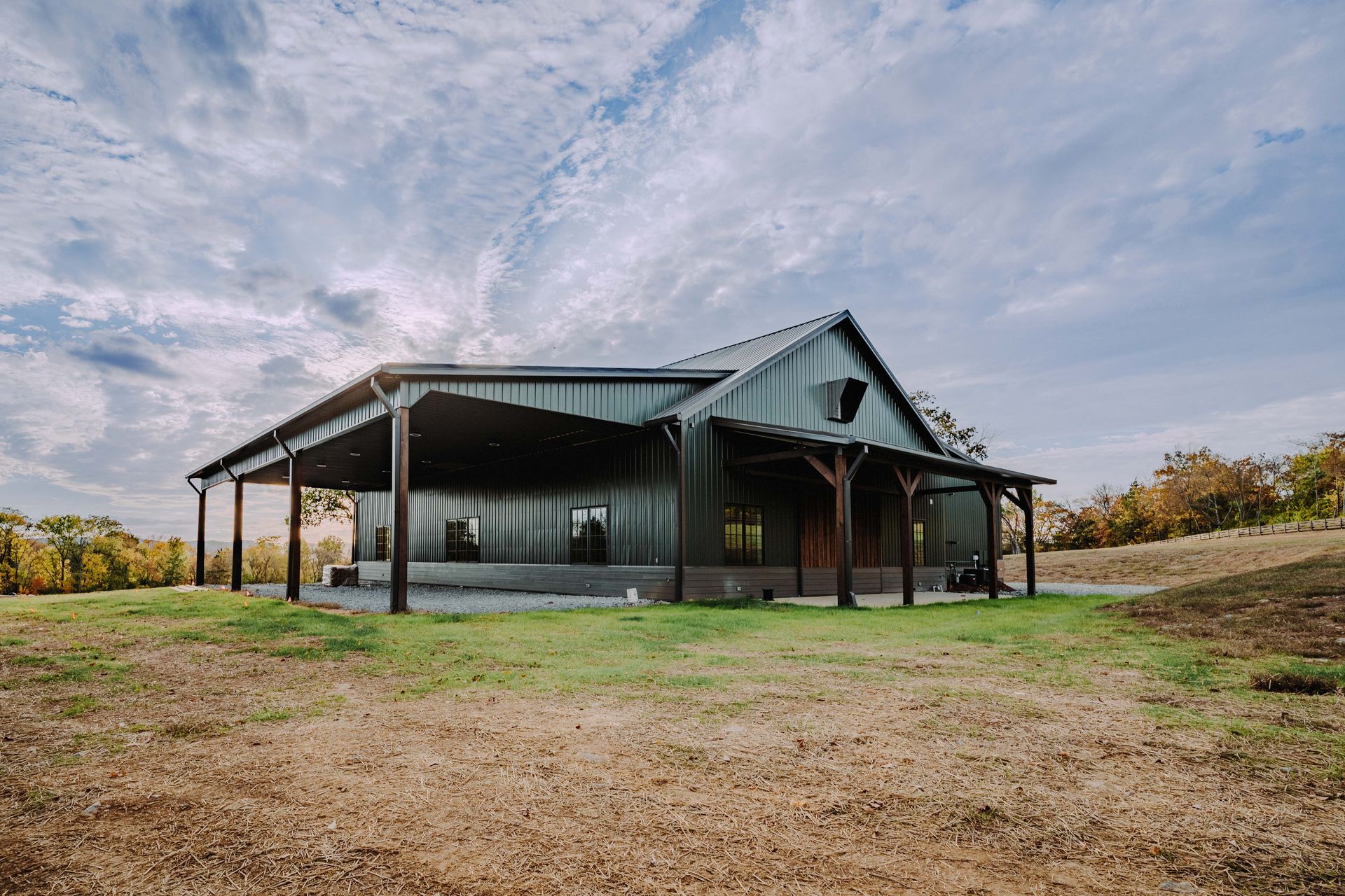 A large house with a porch is sitting on top of a grassy hill.