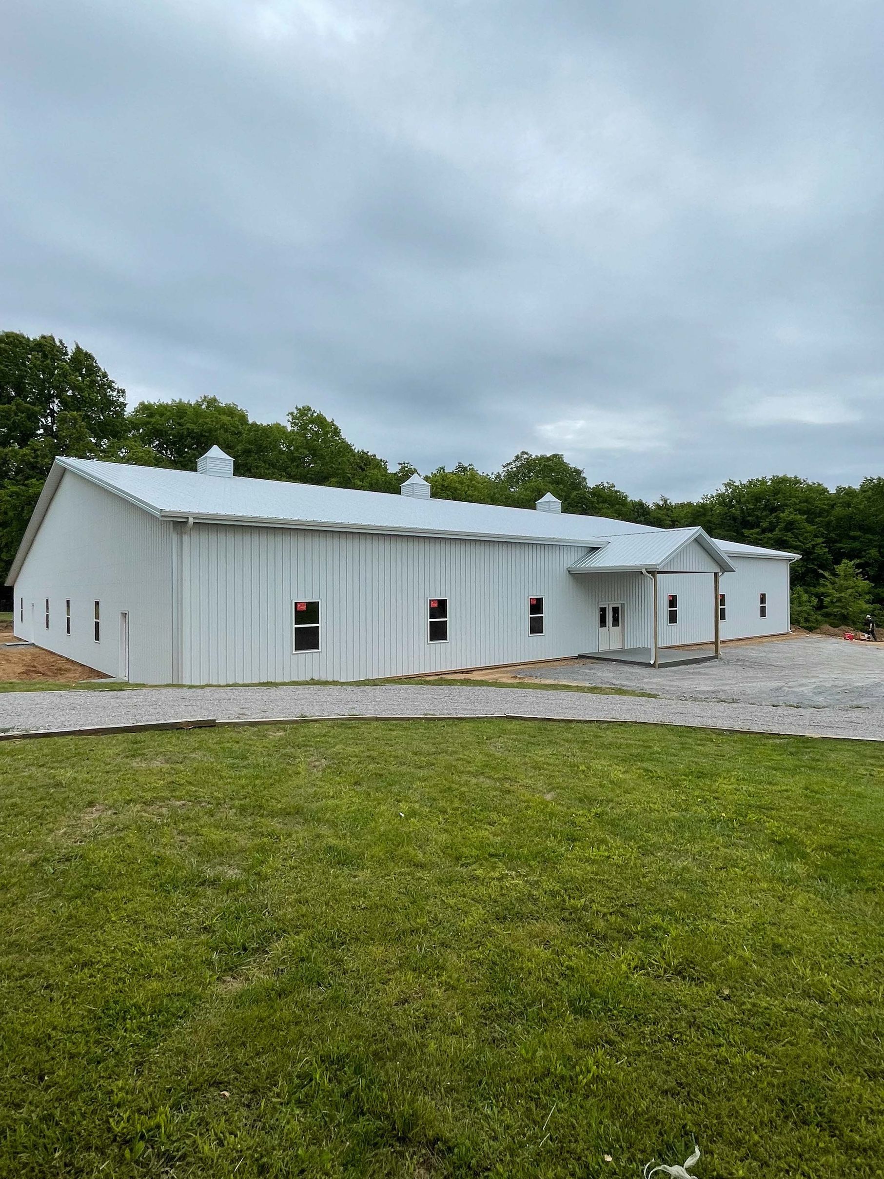 A large white building is sitting on top of a lush green field.