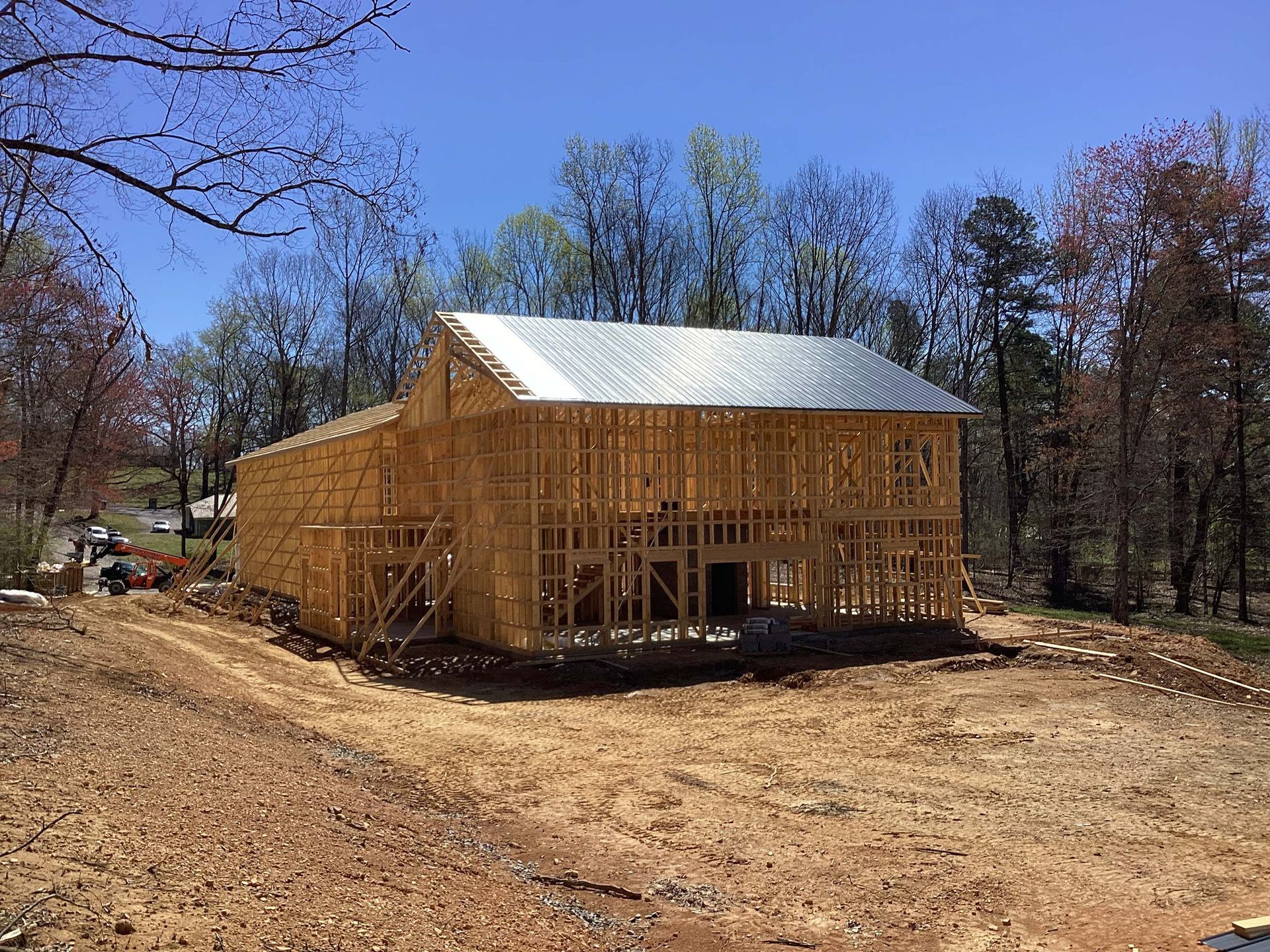 A large wooden house is being built in the middle of a dirt field.