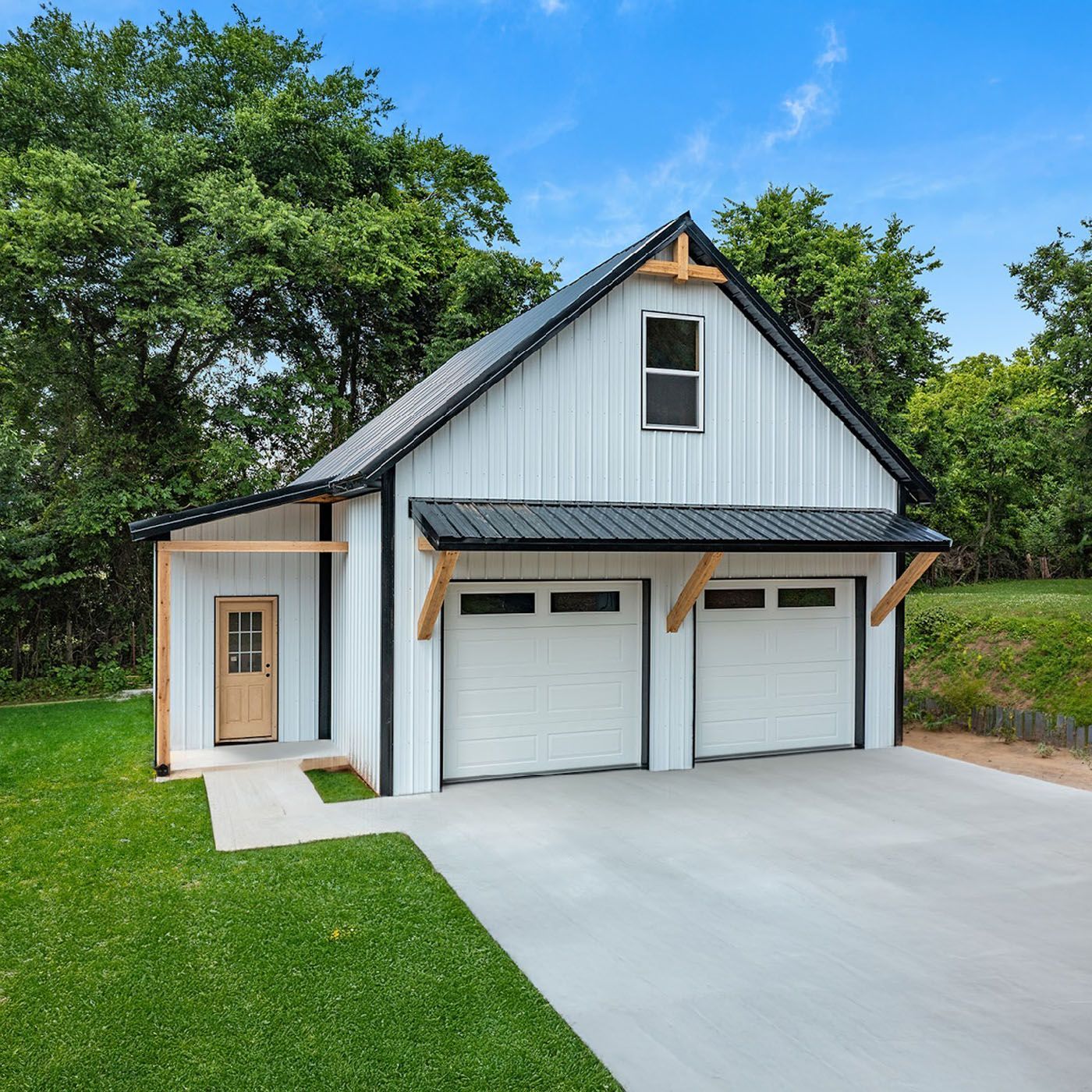 A white house with a brown garage door is sitting on top of a grassy hill.