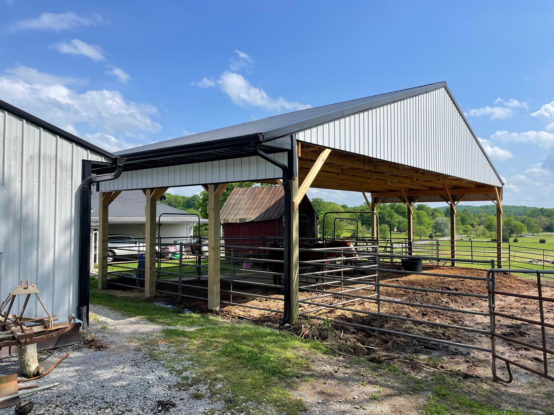 A barn with a white roof is being built on a farm.