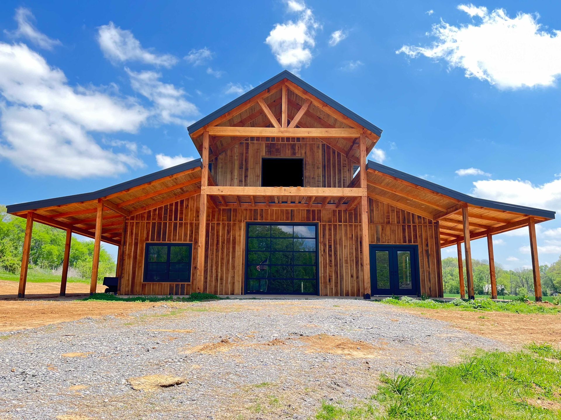 A large wooden barn is sitting on top of a dirt field.