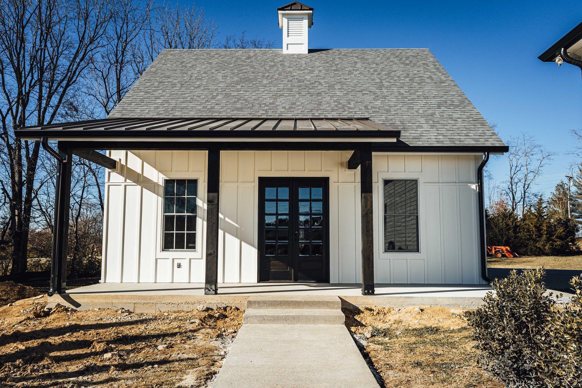 A small white house with a gray roof and a porch.