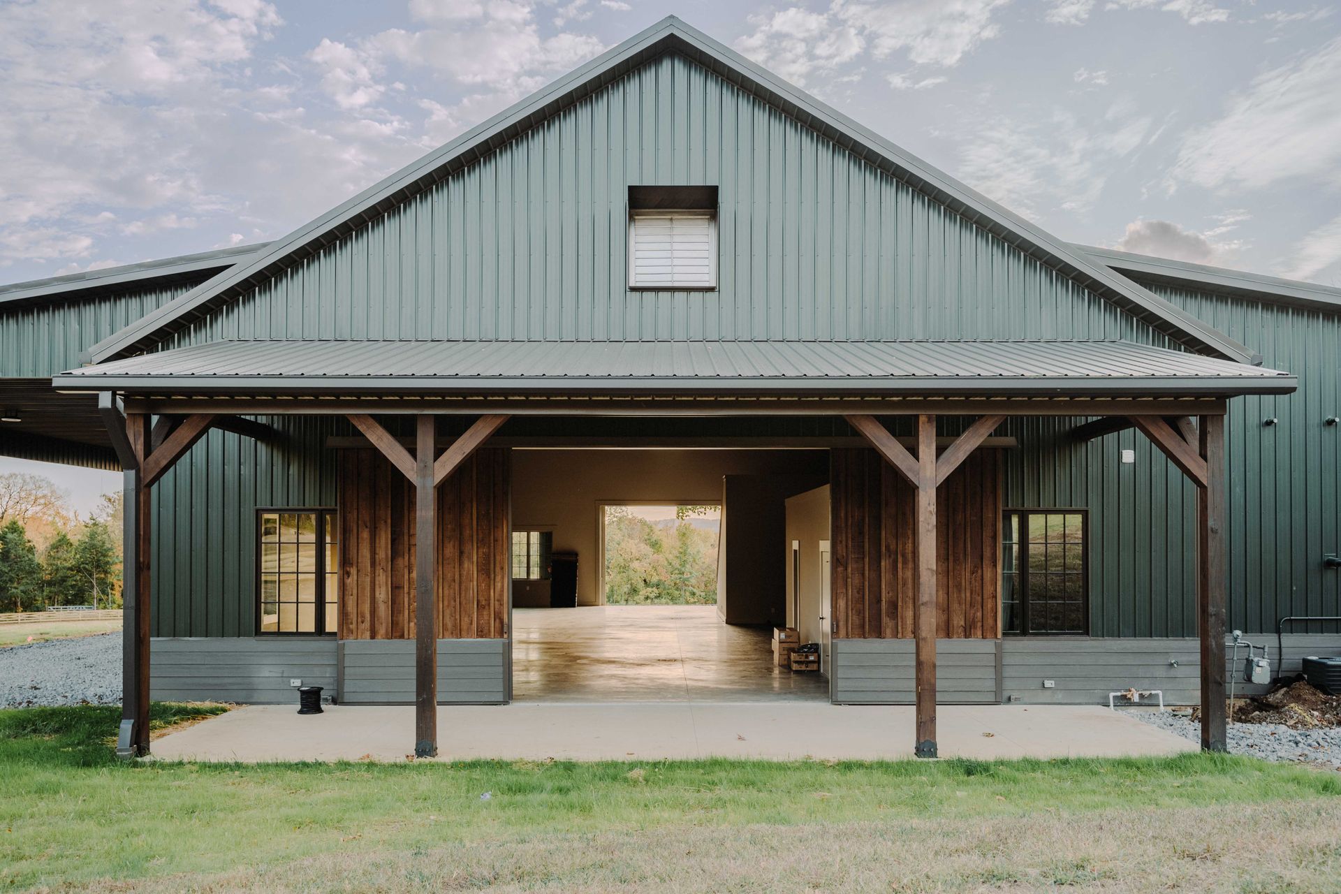 A large green barn with a porch and a sliding door.