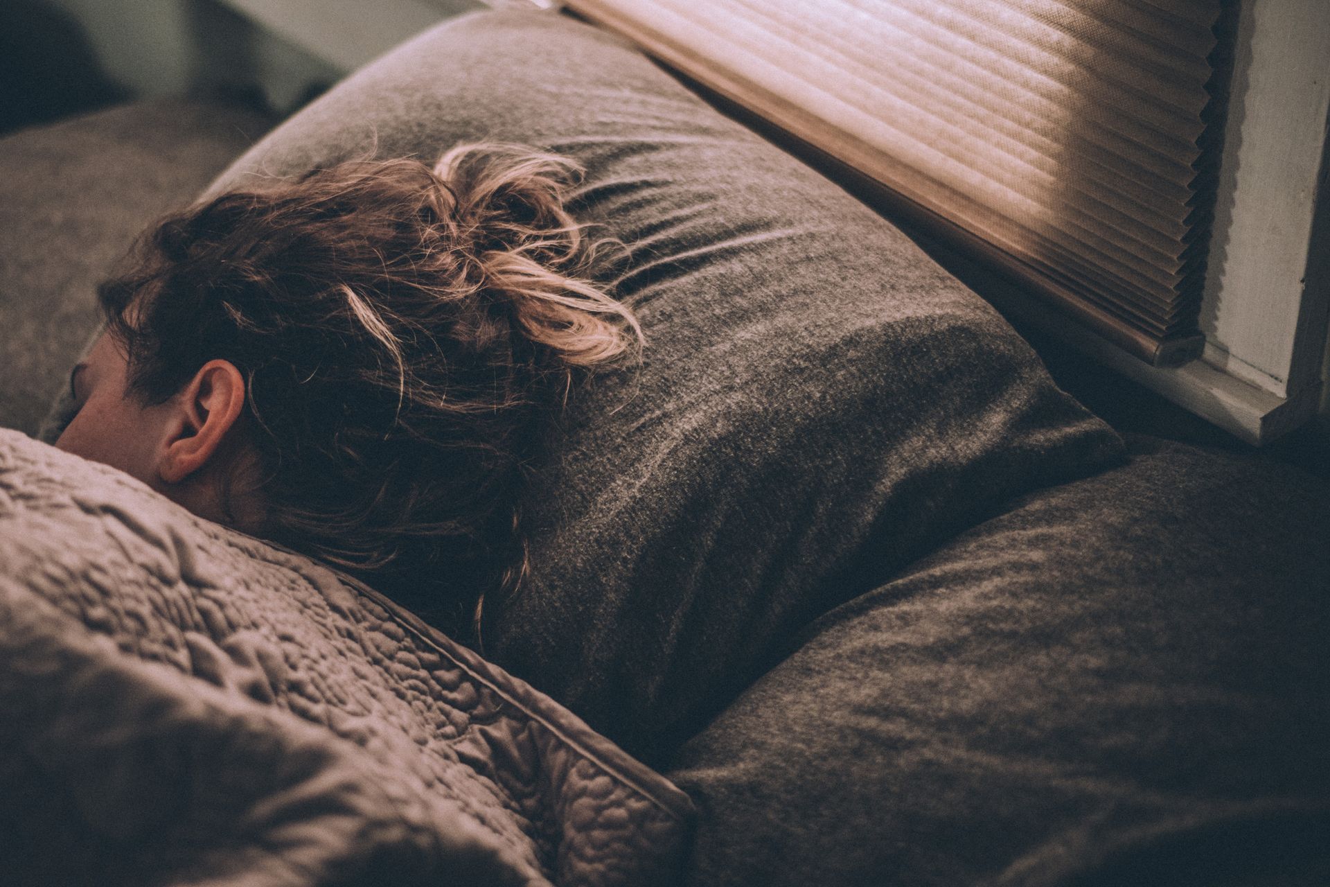 a woman is sleeping on a bed with her head on a pillow .