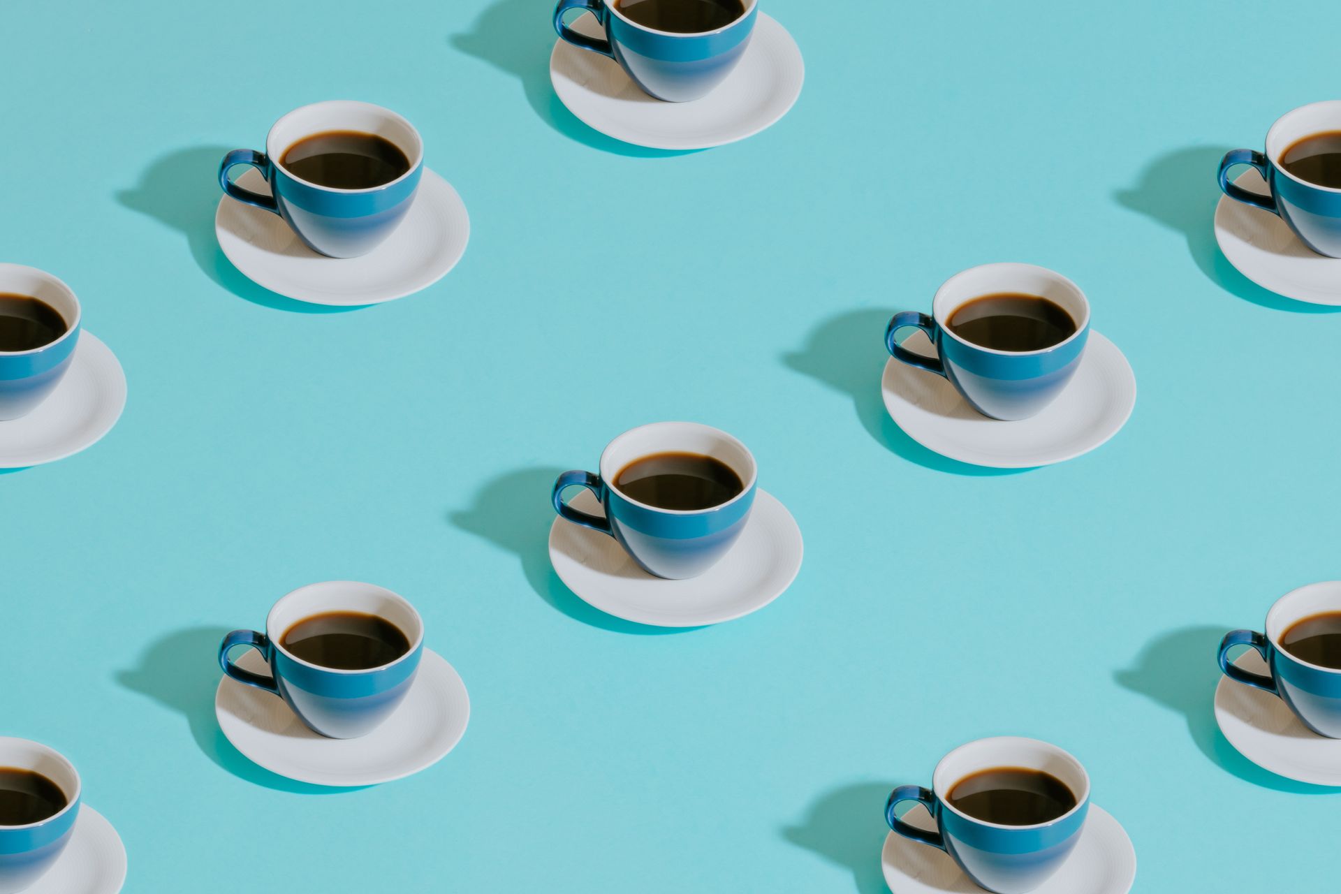 a pattern of cups of coffee on saucers on a blue background .