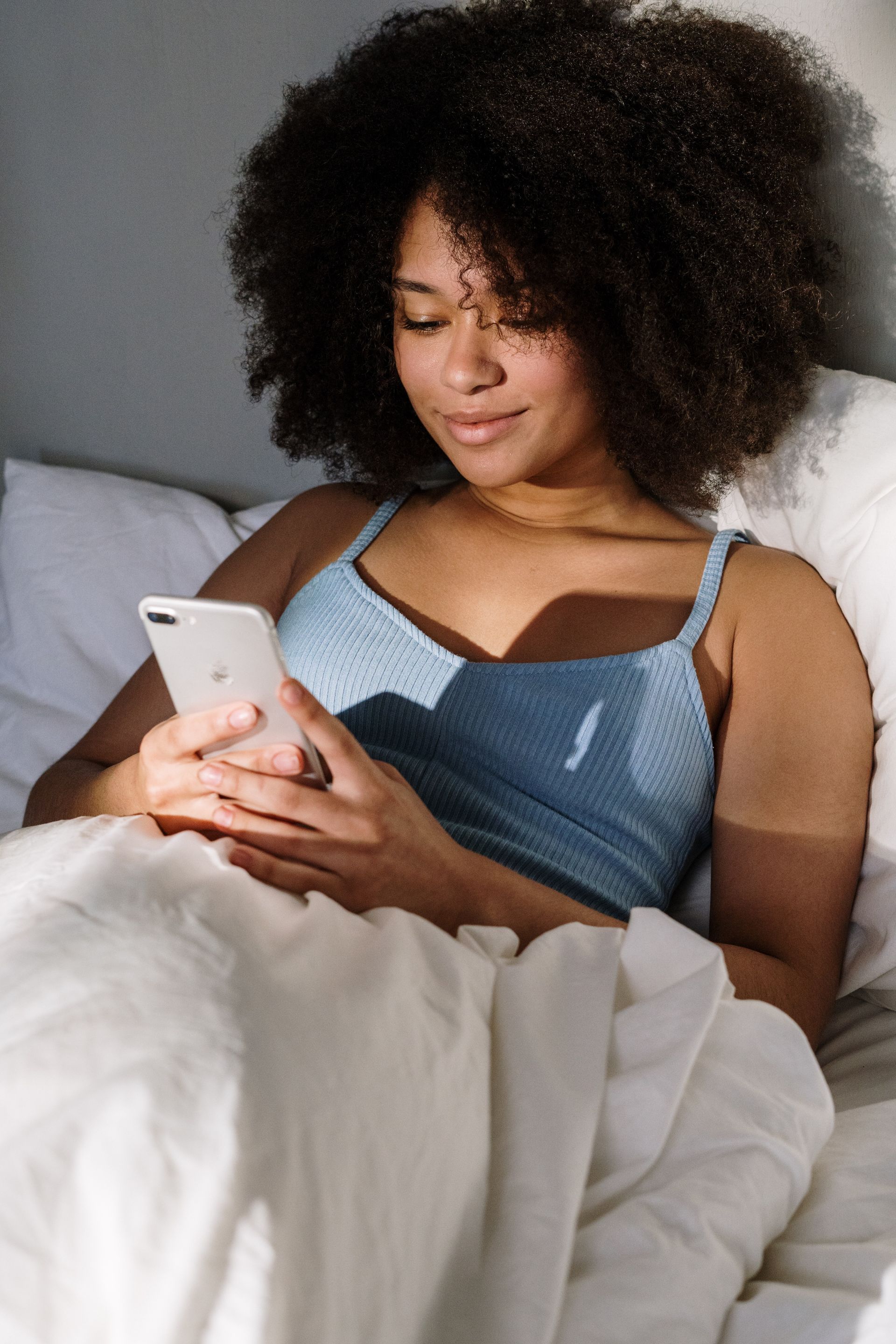 a woman is laying in bed looking at her phone .