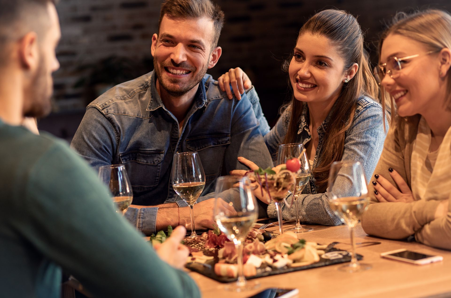 A group of people are sitting at a table with wine glasses and food.