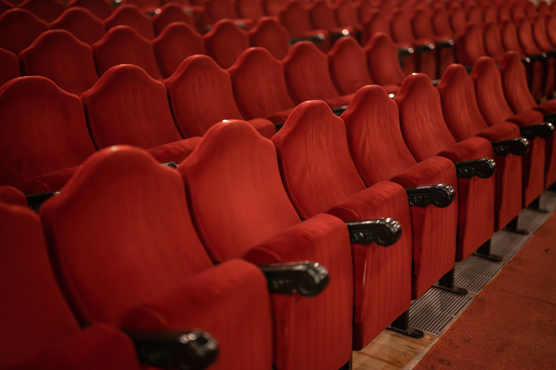 Rows of empty red seats in an auditorium.