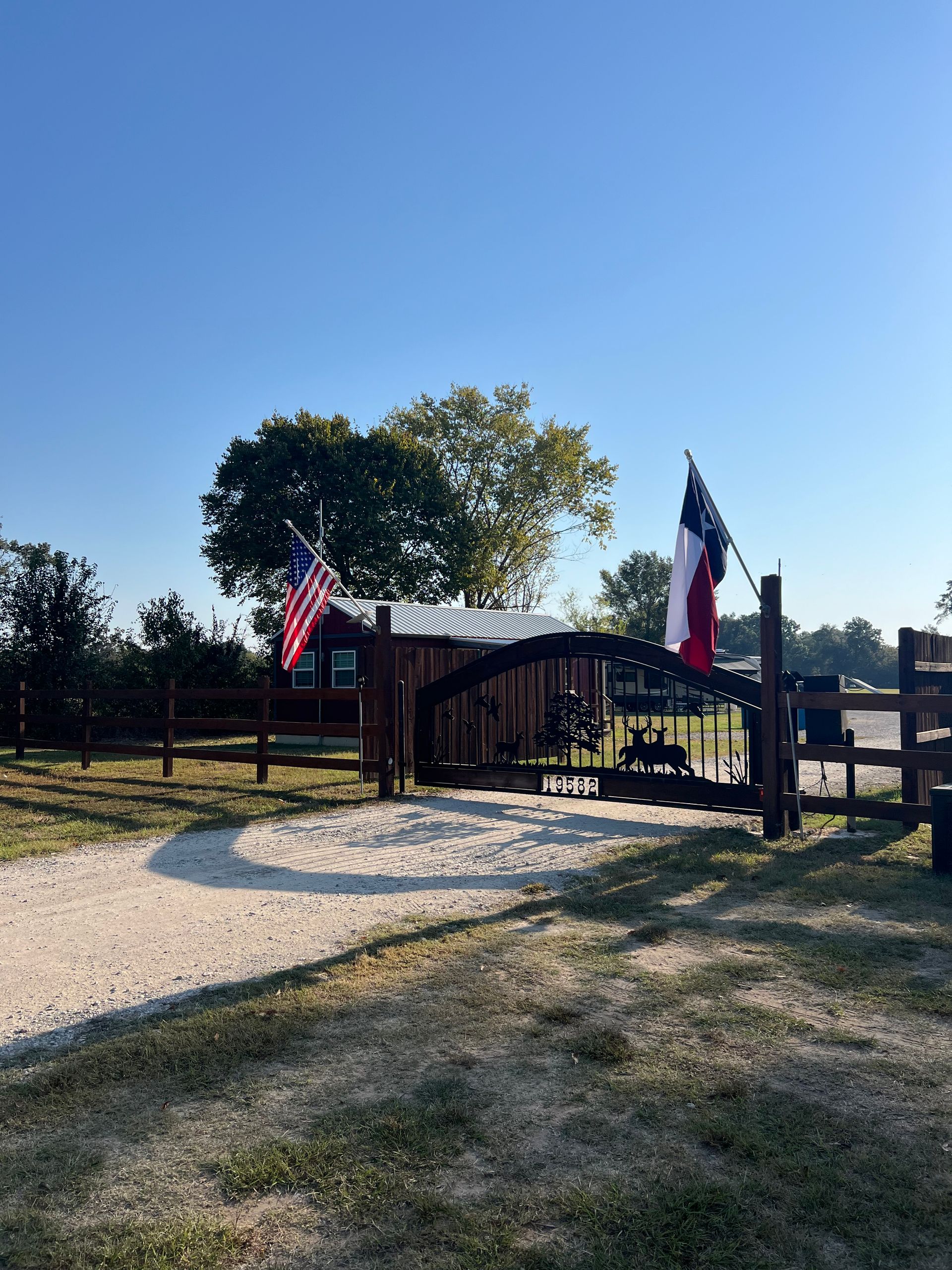 A texas flag and an american flag are flying in front of a house.