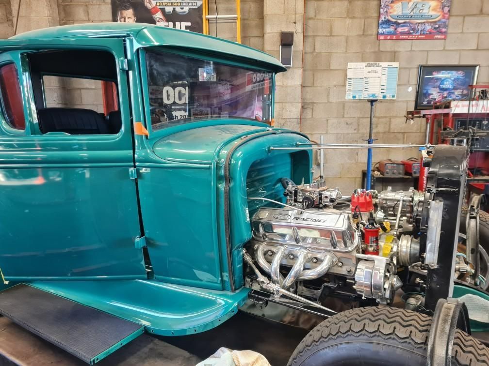 A green truck is sitting on a lift in a garage.