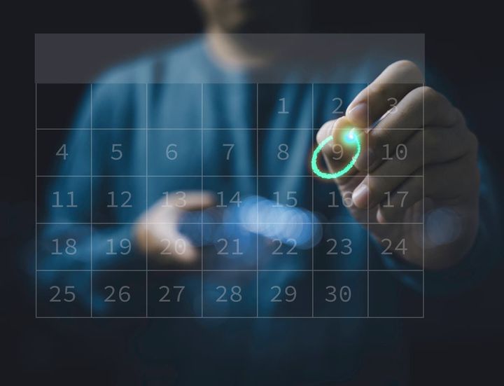 A man is drawing a circle on a calendar with a marker.