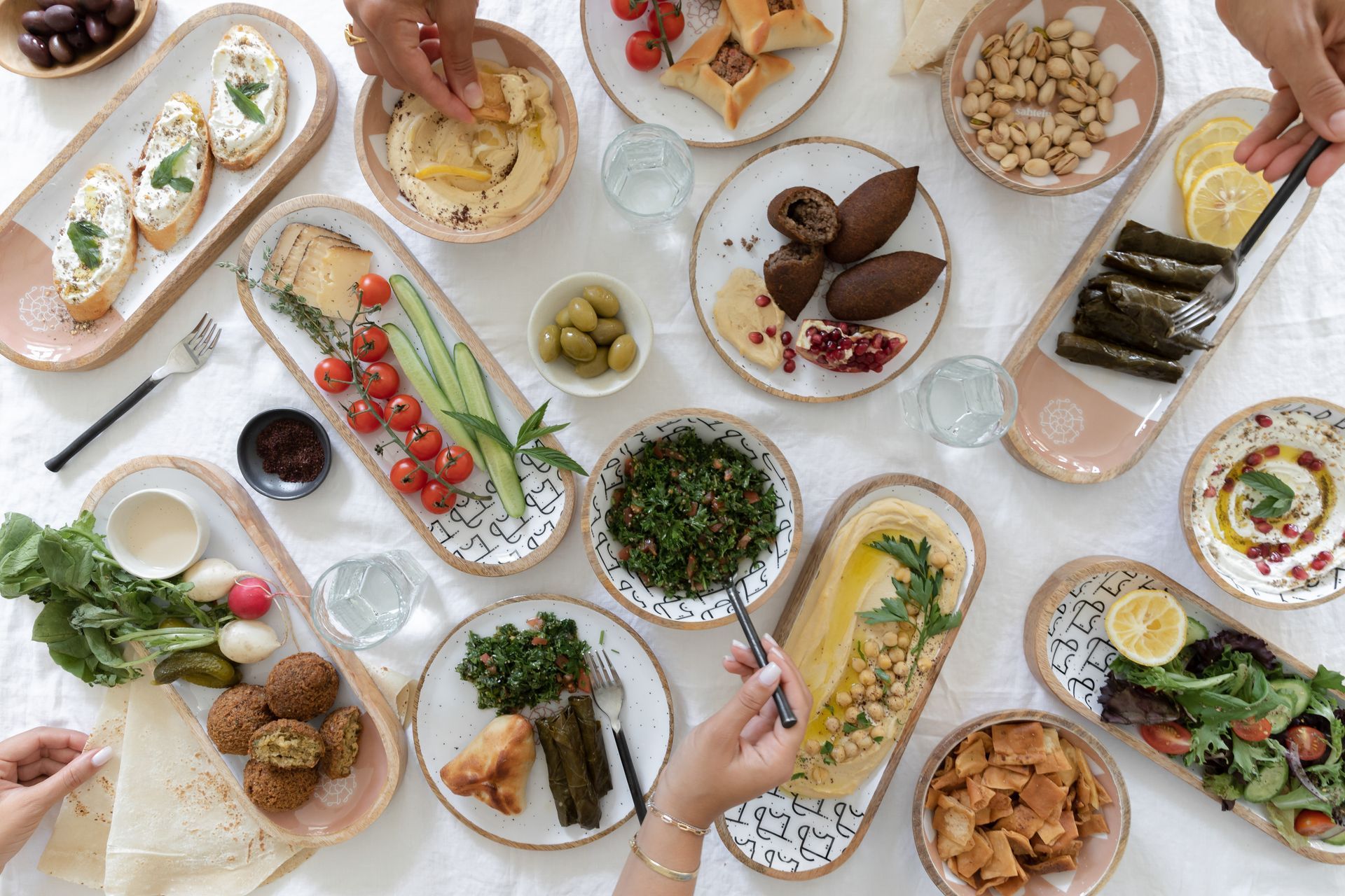 a table topped with plates of food and a person holding a fork