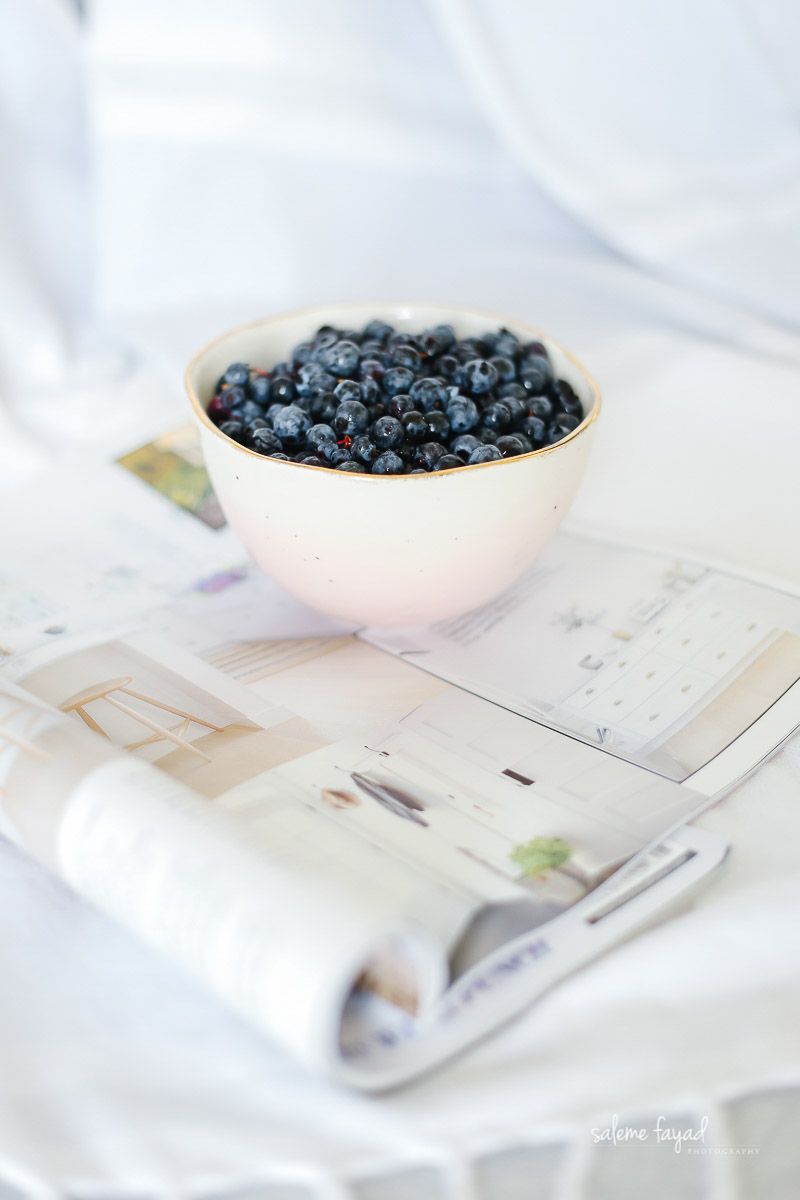 a bowl of blueberries is sitting on top of a magazine