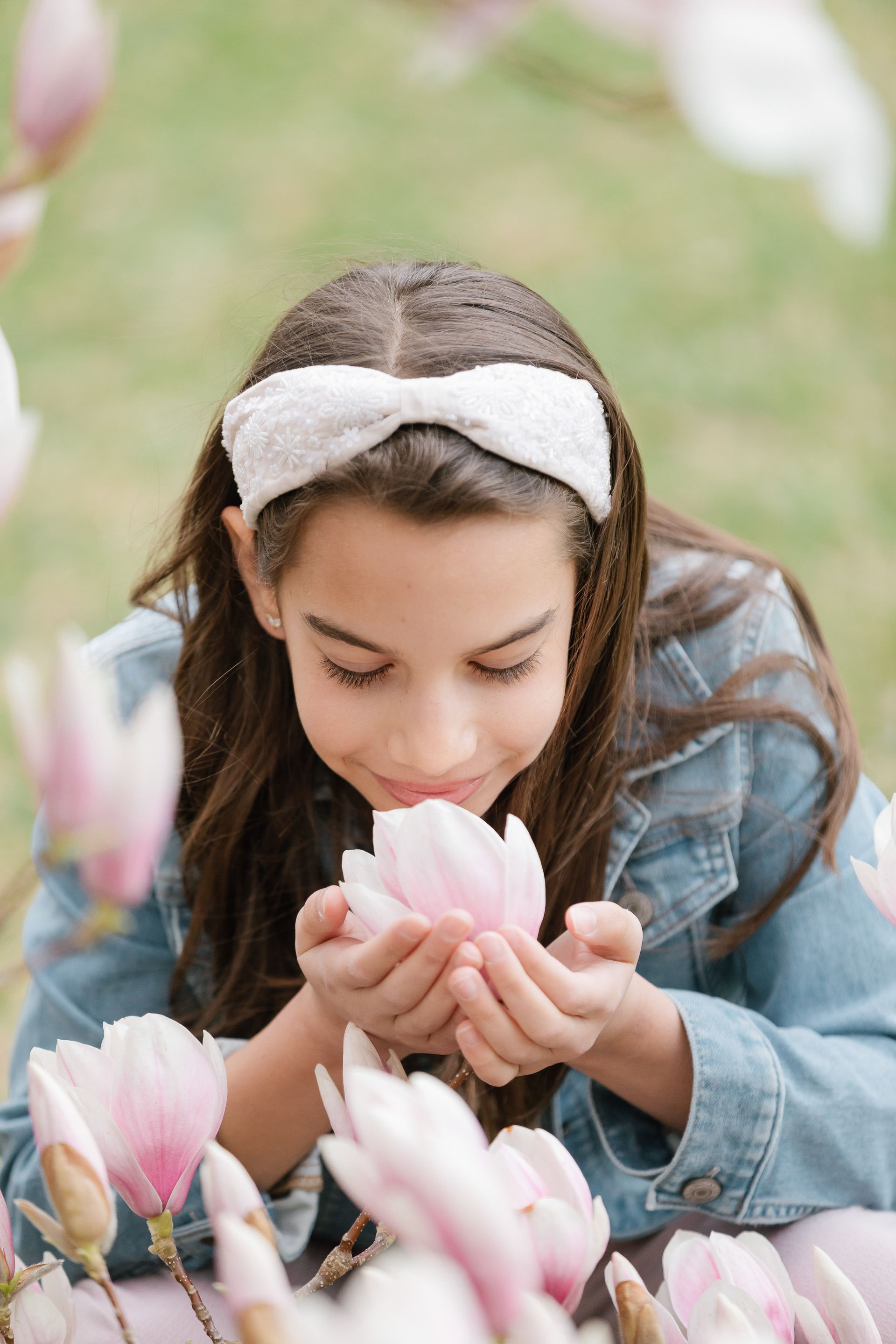 a young girl is holding a pink flower in her hands .