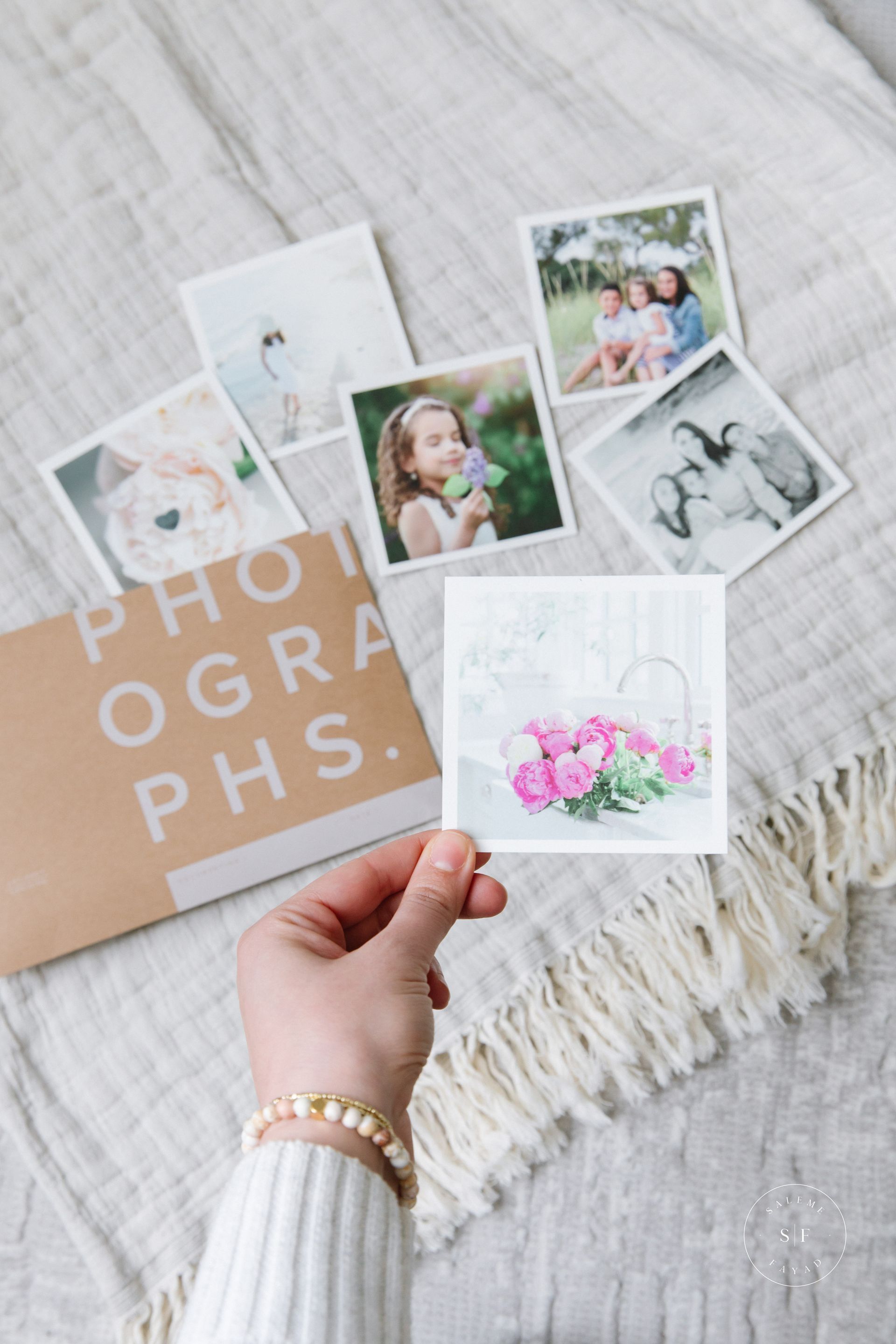 a person is holding a picture of a photo with scattered photo memories in the background