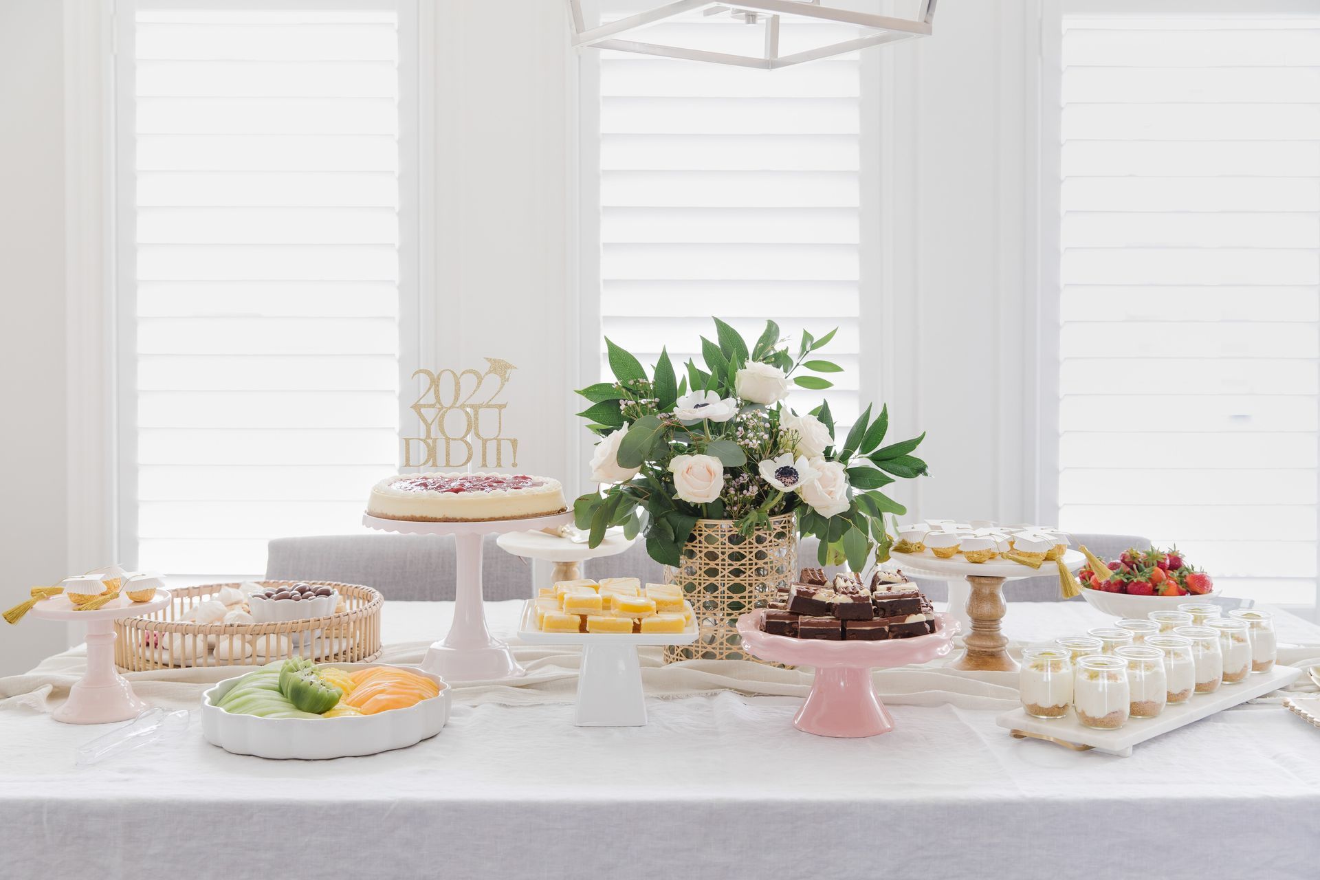 a table topped with a variety of desserts and flowers for a graduation celebration