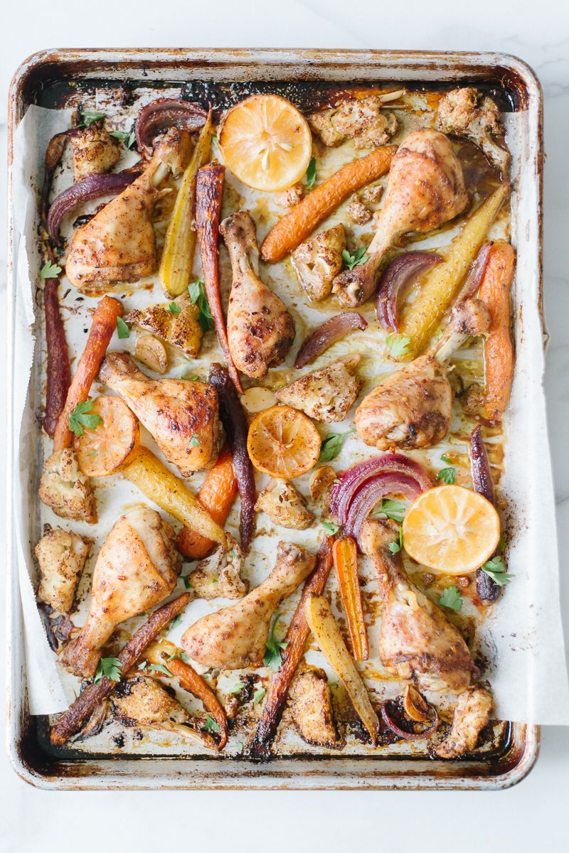 a pan filled with chicken , carrots , onions and lemon slices .