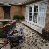 A brick patio under construction with a wheelbarrow full of broken bricks. A brick patio under construction with a wheelbarrow full of broken bricks.