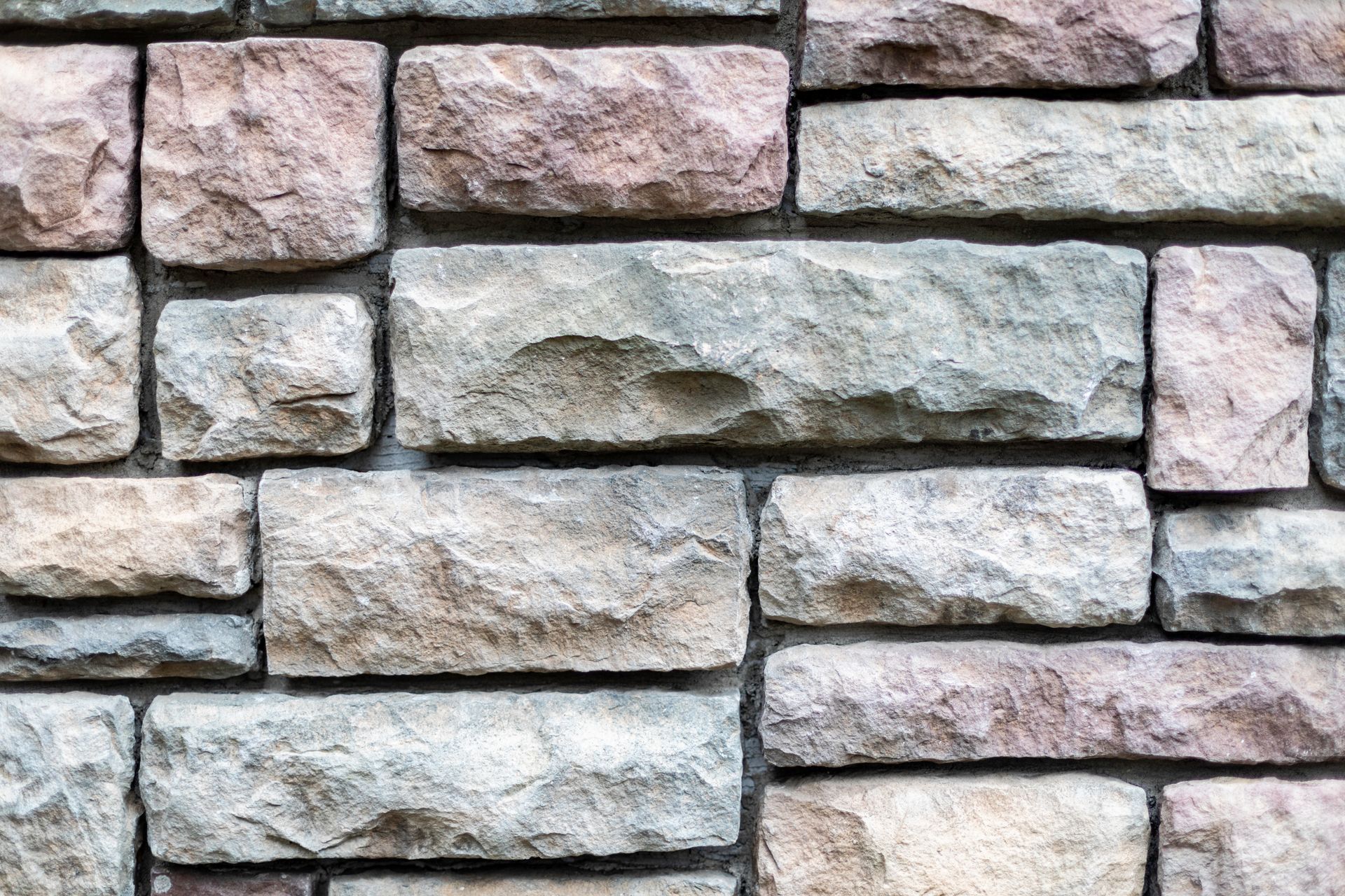 Stone brick wall in varying shades of gray, beige, and pink.